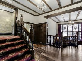 A hallway with wooden stairs and stained glass windows at Tudor Grange in Bournemouth