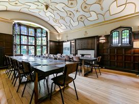 A meeting room with long tables and chairs with wood paneling on walls and decorative ceiling at Tudor Grange in Bournemouth