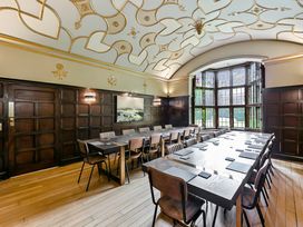 A conference room with a long table and chairs by a large window at Tudor Grange in Bournemouth