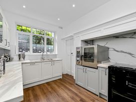 A kitchen with white cabinets wooden floor and stainless steel appliances at Tudor Grange in Bournemouth