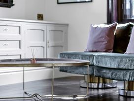 A living room with a round metal coffee table and a velvet sofa with cushions at Tudor Grange in Bournemouth