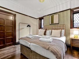A bedroom with a double bed with pillows and towels two windows a wooden door and a lamp on a bedside table at Tudor Grange in Bournemouth