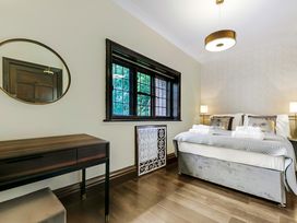 A bedroom with a double bed, bedside lamps, a desk with a round mirror, and a window at Tudor Grange in Bournemouth