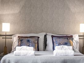A bed with two pillows two decorative cushions and folded towels next to two lamps at Tudor Grange in Bournemouth