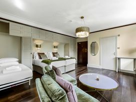 A bedroom with two beds a green sofa a round coffee table a door and a wall mirror at Tudor Grange in Bournemouth