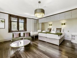 A bedroom with two single beds a pull-out bed two green chairs and a coffee table at Tudor Grange in Bournemouth
