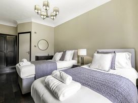 A bedroom with two single beds bedside table with lamp dresser with round mirror at Tudor Grange in Bournemouth