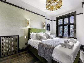 A bedroom with a bed with white linens and a green headboard next to a window with black frames at Tudor Grange in Bournemouth
