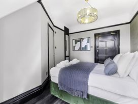 A bedroom with a bed covered by a blue throw and white sheets with pillows and towels on the bed at Tudor Grange in Bournemouth