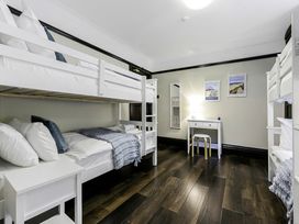 A bedroom with two white bunk beds a white side table and a white desk with a stool at Tudor Grange in Bournemouth
