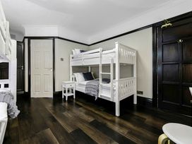 A bedroom with two white bunk beds a small white bedside table and dark wooden doors at Tudor Grange in Bournemouth