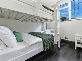 A bedroom with white bunk beds green blanket and pillows next to a window at Tudor Grange in Bournemouth
