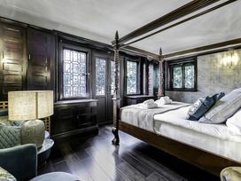 A bedroom with a four-poster bed pillows and rolled towels near a window and lamp at Tudor Grange in Bournemouth