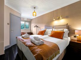 A bedroom with a double bed with orange pillows and blankets bedside tables lamps and a window at Tudor Grange in Bournemouth