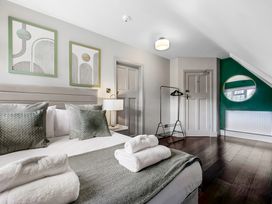 A bedroom with a bed with pillows and folded towels a lamp two doors a clothing rack and a round mirror on a green wall at Tudor Grange in Bournemouth