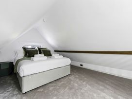 A bedroom with a bed pillows and towels under a slanted ceiling with a wooden beam at Tudor Grange in Bournemouth