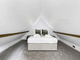 A bedroom with a bed centered under a sloped ceiling and wooden beams at Tudor Grange in Bournemouth