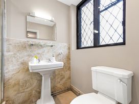 A bathroom with a pedestal sink a toilet a mirror and a window with lattice design at Tudor Grange in Bournemouth