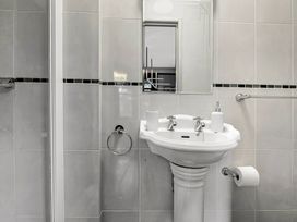 A bathroom with a pedestal sink a mirror and tiled walls at Tudor Grange in Bournemouth