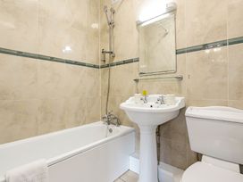 A bathroom with a bathtub shower sink mirror and toilet at Tudor Grange in Bournemouth