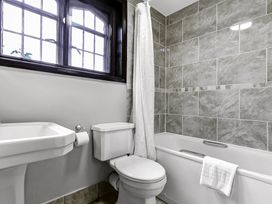 A bathroom with a bathtub with towel a toilet and a sink under a window at Tudor Grange in Bournemouth