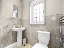 A bathroom with a pedestal sink mirror toilet window and a towel rack at Tudor Grange in Bournemouth
