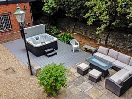 An outdoor patio area with a hot tub sofa seating table and chairs at Tudor Grange in Bournemouth