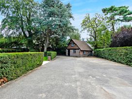 A small brick house with a pitched roof surrounded by trees and hedges at Tudor Grange in Bournemouth