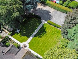 A garden with a paved path a round patio table with chairs and surrounding trees at Tudor Grange in Bournemouth
