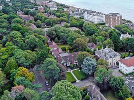 An aerial view of houses surrounded by trees near the coast at Tudor Grange in Bournemouth