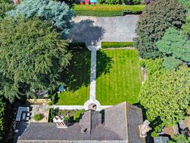 Aerial view of a garden with a lawn stone paths trees hedges and patio furniture at Tudor Grange in Bournemouth