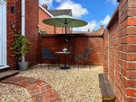 A garden with a table and chairs under an umbrella at 8 Biddlecombe Orchard Bridport