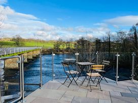 An outdoor seating area with a table and chairs near a river at Bridge End Cottage in Wark