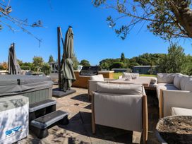 An outdoor seating area with hot tub and barbecue at The Farmhouse in St. Osyth