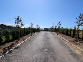 A roadway leading to a gate with trees lining the sides at The Farmhouse in St. Osyth