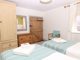 A bedroom with twin beds and a wooden wardrobe at Apple Mill in Venn Ottery near Sidmouth