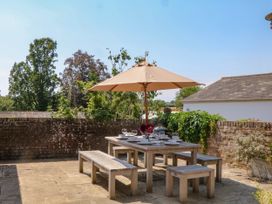 An outdoor dining area with a table and umbrella at Apple Mill in Venn Ottery near Sidmouth