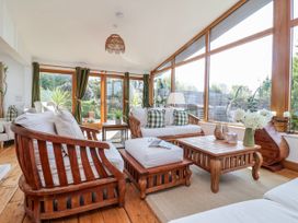 A sunroom with wooden furniture and large windows at Burlodge Swimbridge near Barnstaple