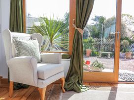 A conservatory with an armchair and a view of a garden at Burlodge in Swimbridge near Barnstaple