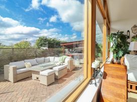 A conservatory with a sofa and coffee table overlooking a patio at Burlodge Swimbridge near Barnstaple
