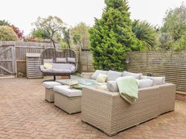 An outdoor seating area with a sofa and hanging chair at Burlodge Swimbridge near Barnstaple