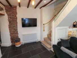 A room with a wall mounted TV radiator staircase and part of a sofa at The Nook in Brixham
