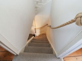 A carpeted staircase with a rope handrail and white walls at The Nook in Brixham