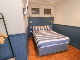 A bedroom with a double bed striped bedding blue wainscoting and wooden floor at The Nook in Brixham
