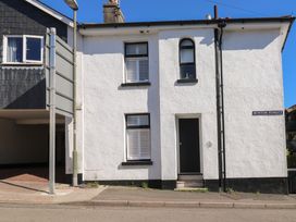 The front exterior of a white building with black door and three windows on Burton Street