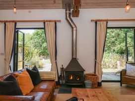 A living room with a wood stove and large windows at Burrows in Venn Ottery near Sidmouth