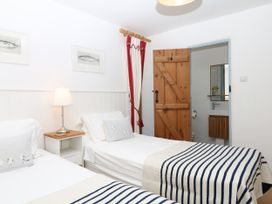 A bedroom with two beds and a wooden door at Burrows in Venn Ottery near Sidmouth