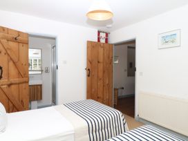 A bedroom with two beds and doors leading to another room at Burrows Venn Ottery near Sidmouth