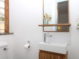 A bathroom with a sink, toilet, and mirror at Burrows in Venn Ottery near Sidmouth