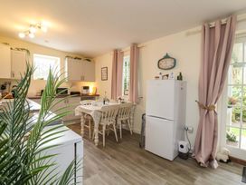 A kitchen with a dining table and refrigerator at Sunset Cottage in Swimbridge near Barnstaple